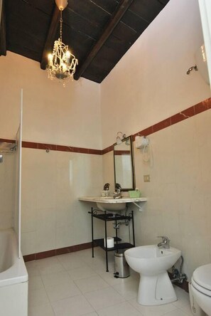 Un baño con ducha, lavabo con espejo, bidé e inodoro.