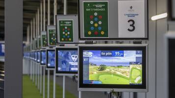 A golf simulation setup with multiple screens displaying golf courses and yardage information.