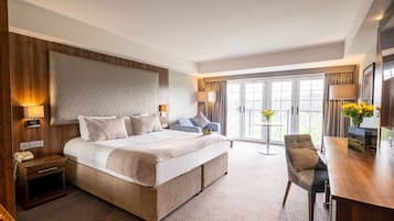 Una habitación de hotel con una cama grande, un escritorio, una silla y un balcón con vistas.