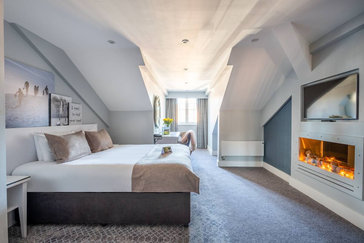 Ein modernes Schlafzimmer mit einem großen Bett, einem Kamin und einem Fernseher.