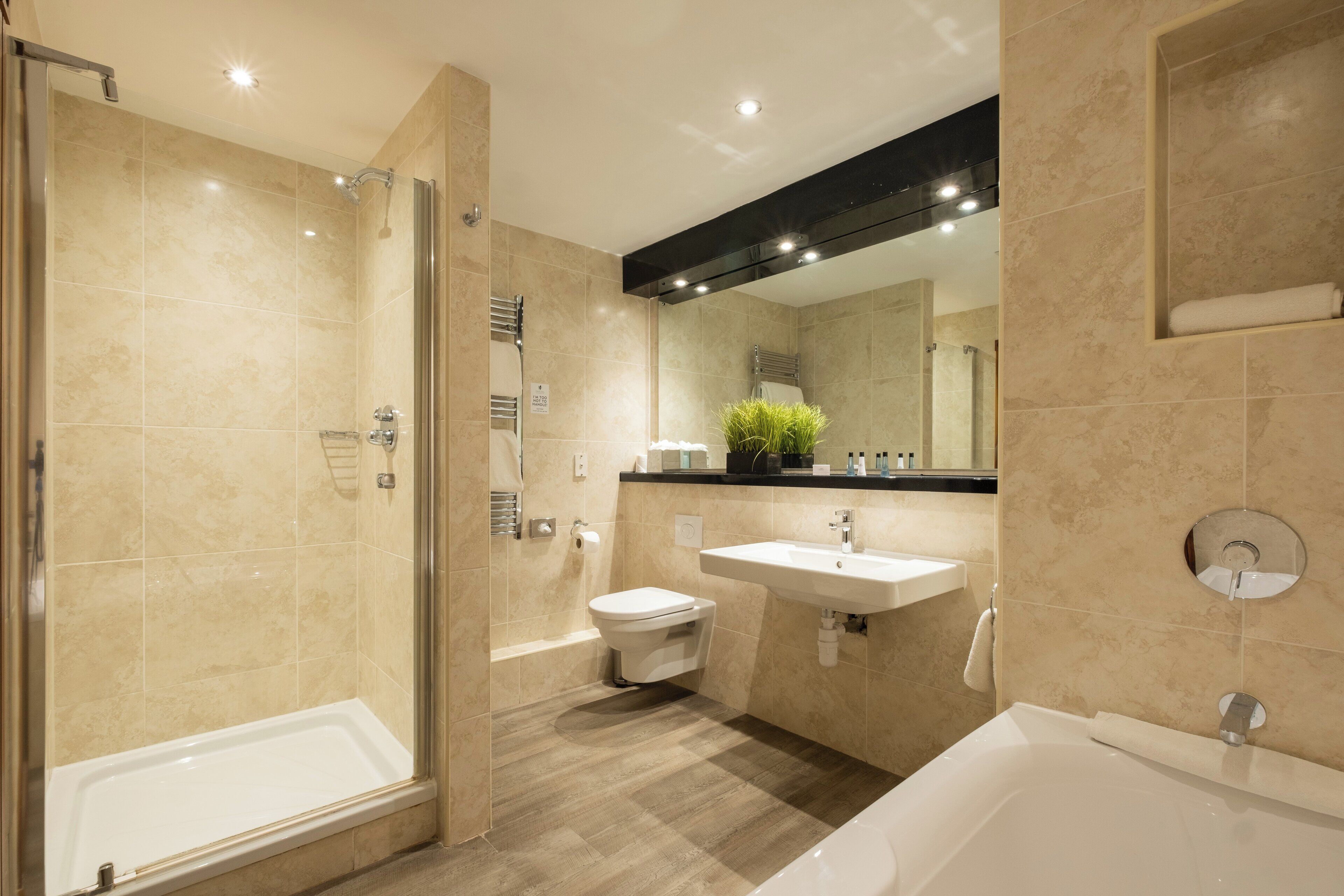 A modern bathroom with a walk-in shower, a bathtub, and a sink.