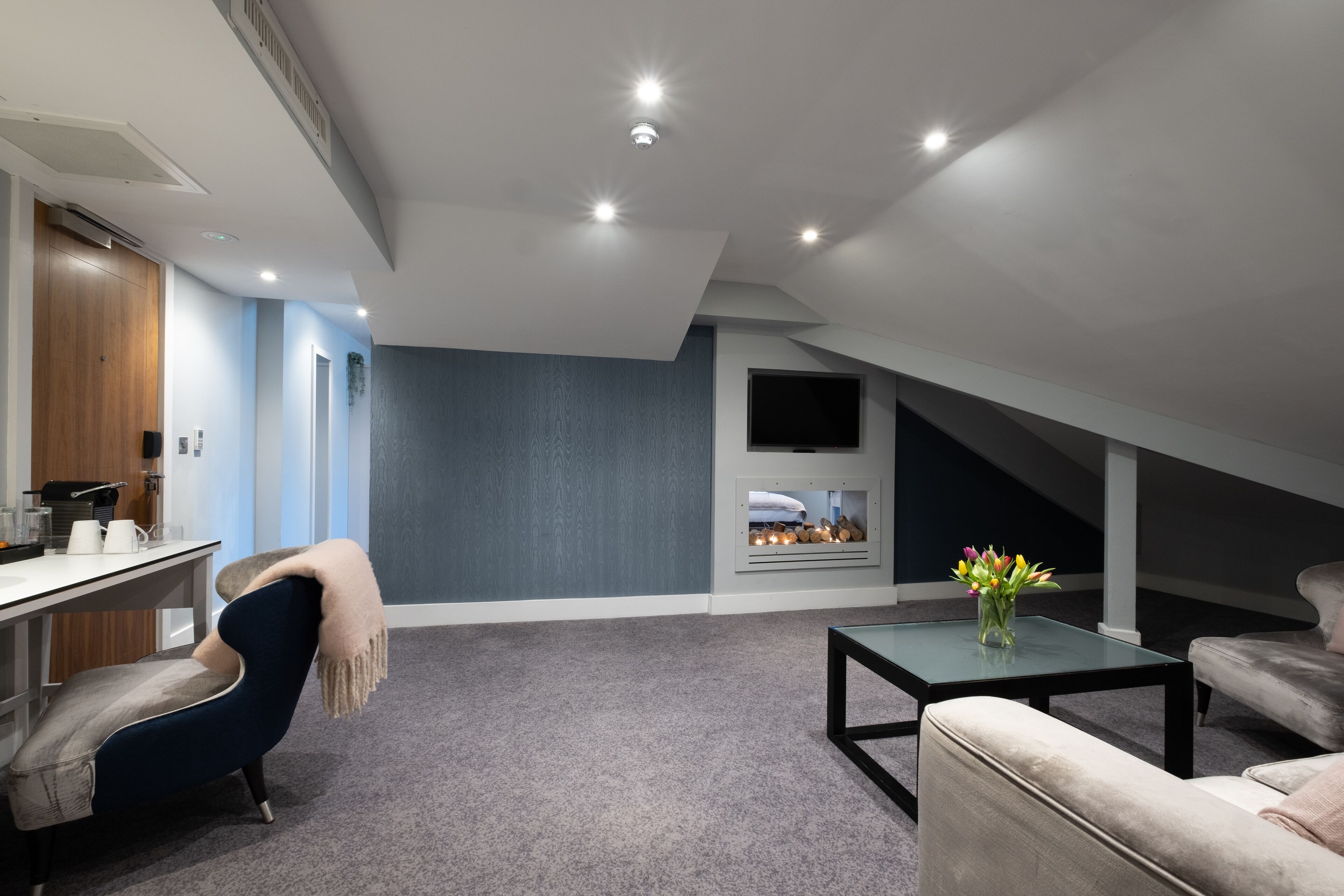 Una sala moderna con una pared de acento azul oscuro, una chimenea y una zona de estar acogedora.
