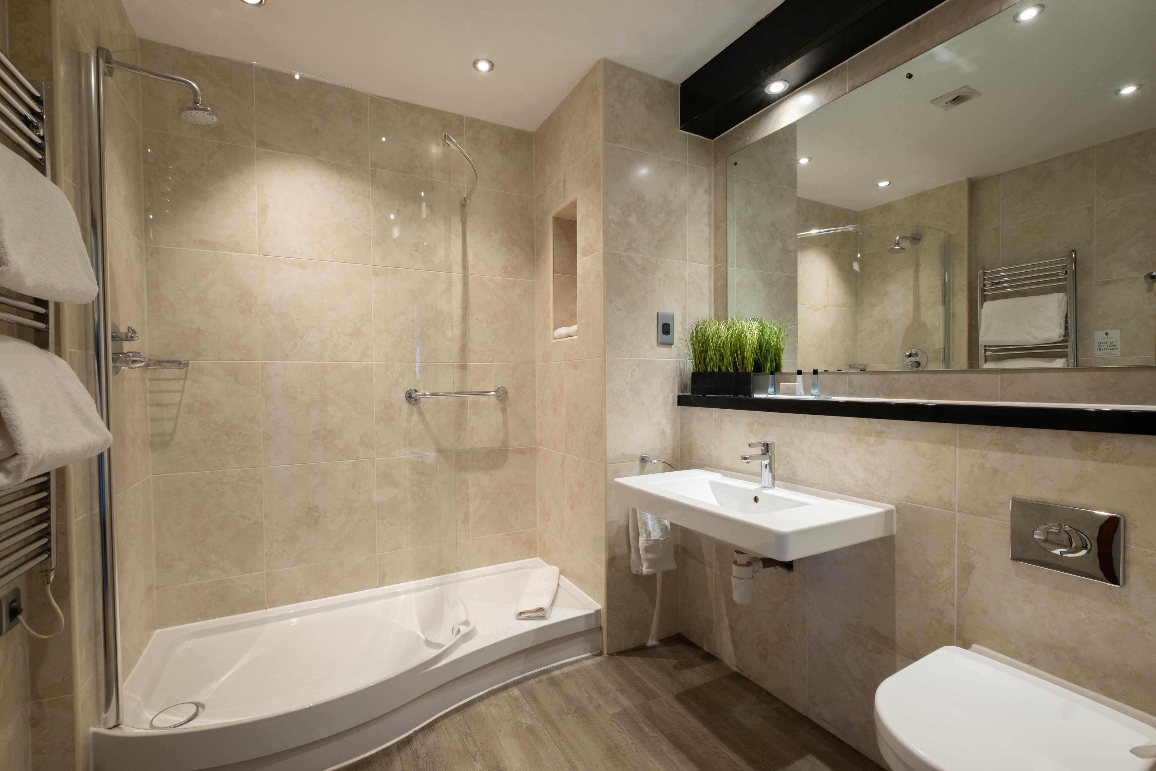 Une salle de bain moderne dotée d’une douche à l’italienne, d’une baignoire sur pieds, d’un lavabo et de toilettes.