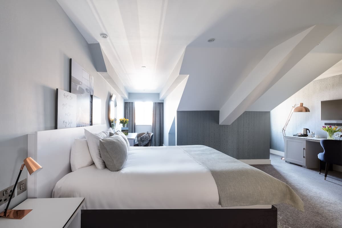 Ein modernes Hotelzimmer mit einem großen Bett, einem Schreibtisch und einer Küchenzeile.