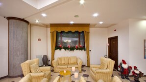Una sala de estar con un sofá, sillones y una mesita de centro. Hay velas sobre la mesa y una decoración navideña en la pared.