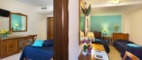 A hotel room with a bed, desk, chair, and a mirror.