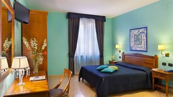 Une chambre d’hôtel équipée d’un lit, d’une table de chevet, d’une lampe, d’une chaise et d’un téléviseur fixé au mur.