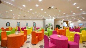Una habitación luminosa con varias mesas y sillas redondas, cada conjunto en un color diferente.
