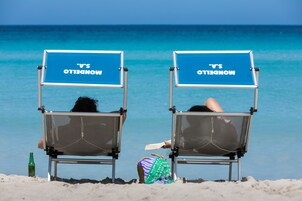 Una spiaggia nelle vicinanze, sabbia bianca, lettini da mare, ombrelloni