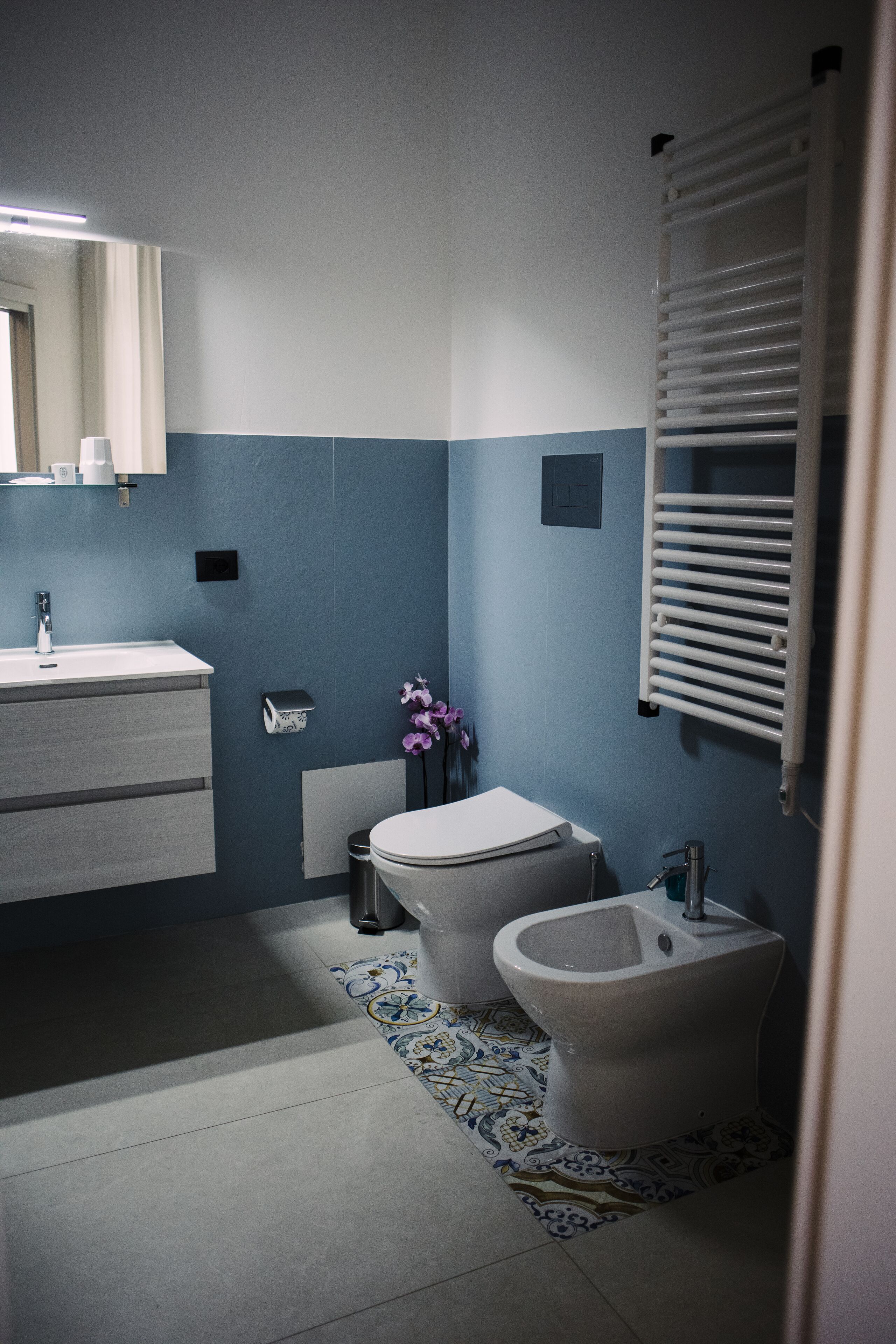 Een badkamer met toilet, bidet, wastafel en een handdoekhouder.