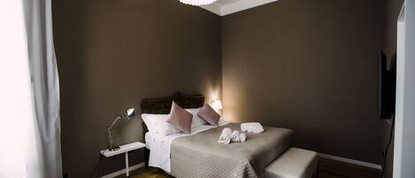 A bedroom with a bed, bedside table, lamp, and a television.