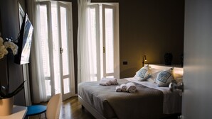 Una habitación de hotel con cama, escritorio, silla y televisión.