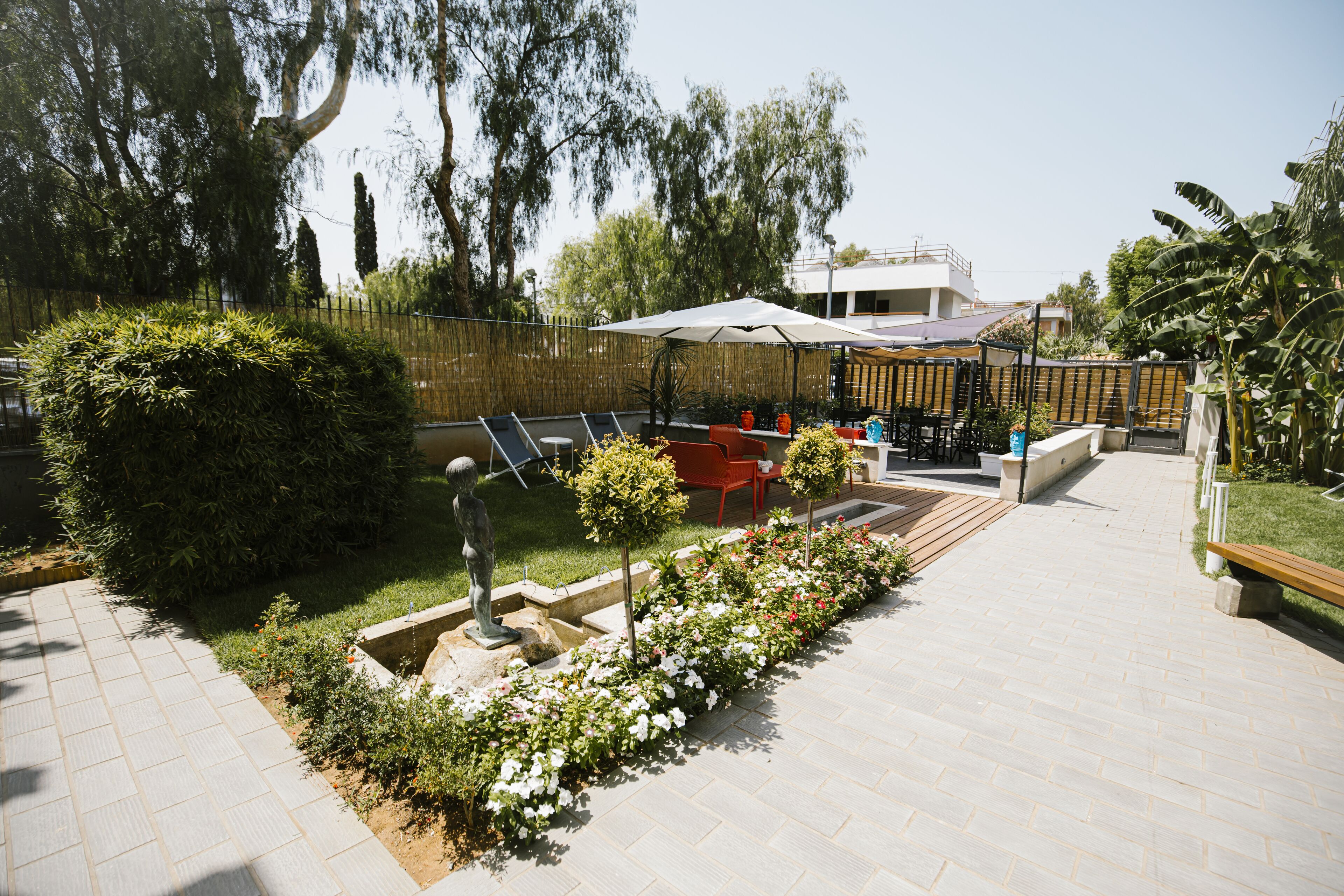 A patio area with a seating arrangement, a small garden with flowers, and a fence.