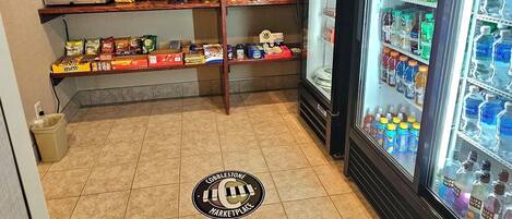 Zona de máquinas expendedoras con Pepsi y Mountain Dew, estantes llenos de snacks y bebidas, y el logotipo de Cobblestone Marketplace en el suelo.