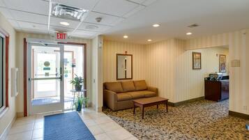 A hotel lobby with a reception desk, a sofa, a coffee table, and a patterned carpet.