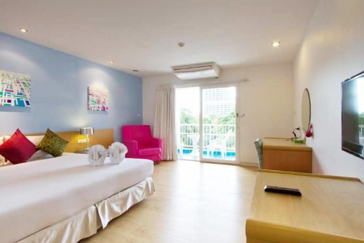 Ein Hotelzimmer mit Bett, Schreibtisch, Stuhl, Fernseher und einem Balkon mit Blick.