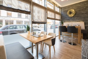 A modern interior with a wooden table, chairs, and a bar area with stools.