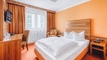 Una habitación de hotel con una cama grande, un escritorio, una silla y un televisor.