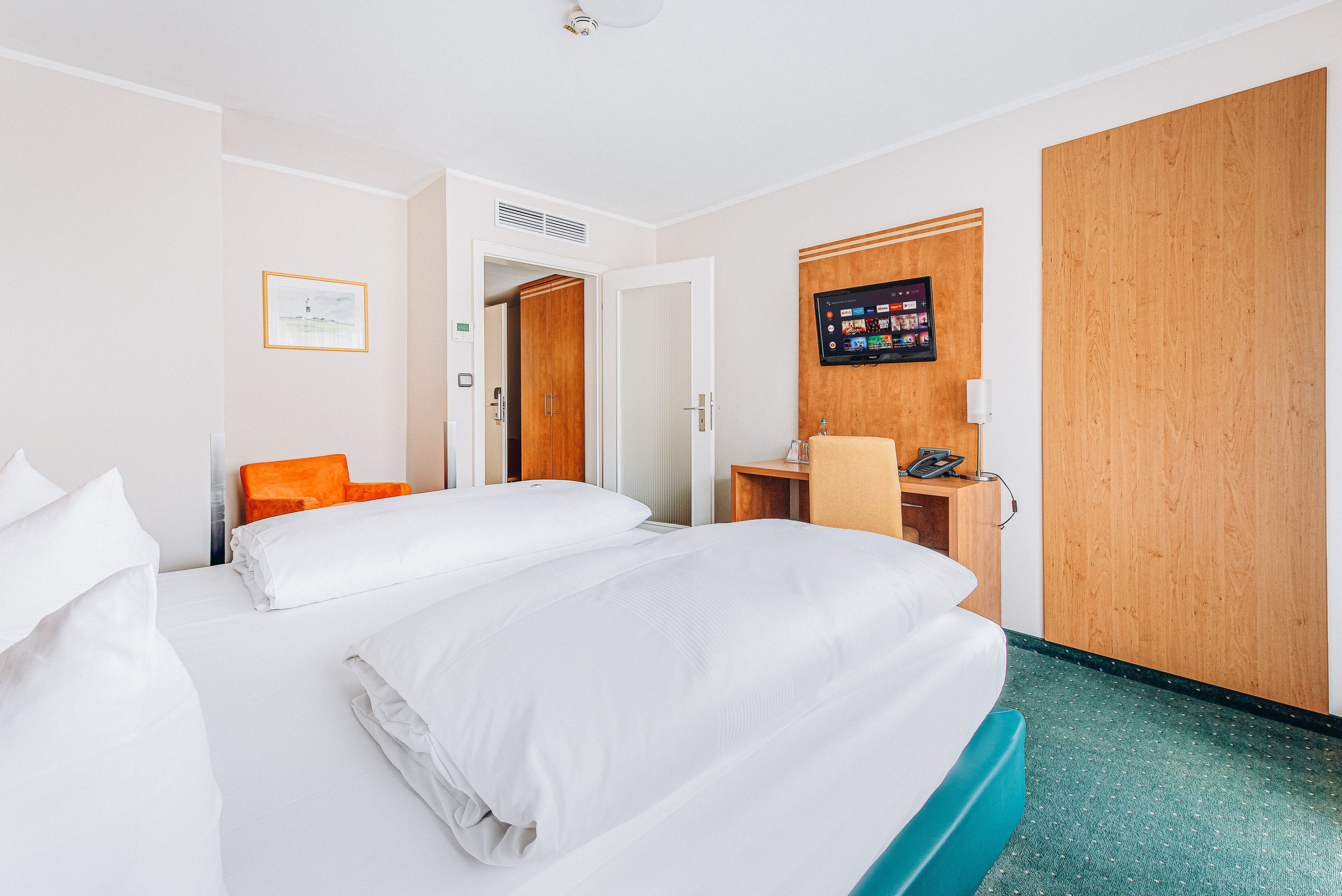 A hotel room with two beds, a desk, a television, and a wardrobe.