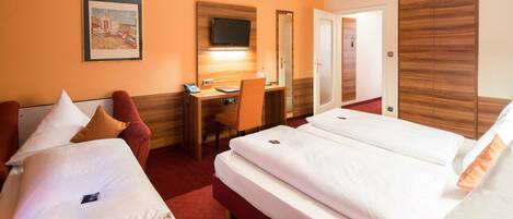 A hotel room with two beds, a desk with a chair, a television, and a wardrobe.
