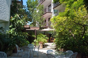 A courtyard with outdoor seating, potted plants, and a staircase leading to an upper floor. - Hotel La Pergola (Rome)