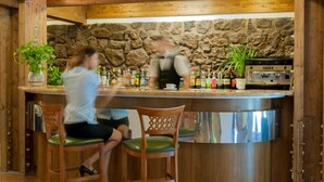 Una zona de bar con vigas de madera, pared de piedra y una máquina de café.