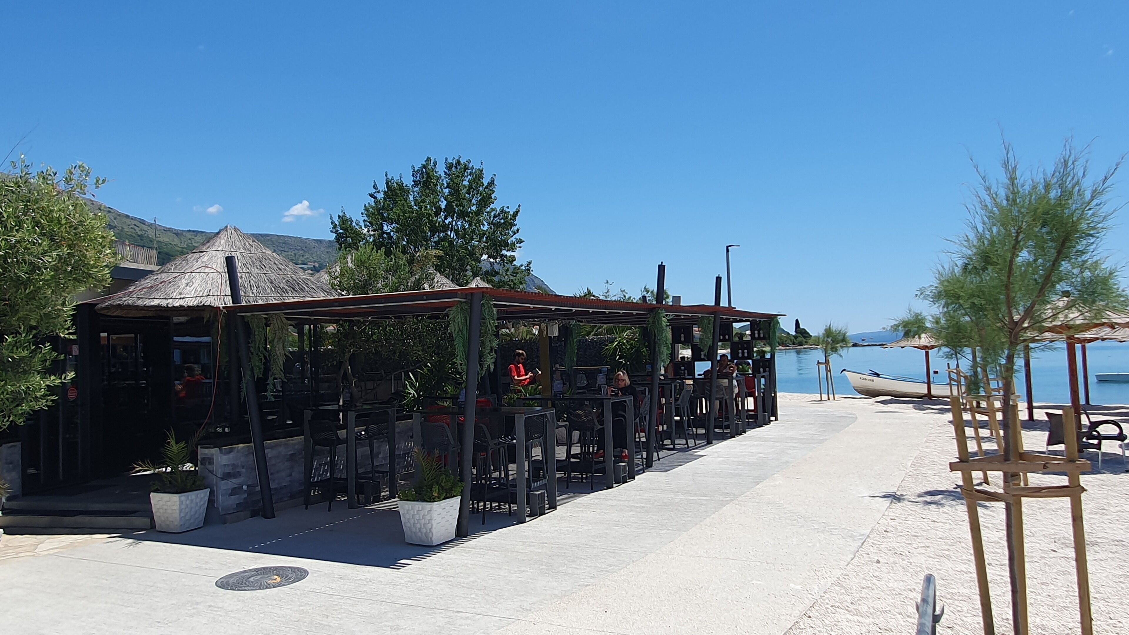 En restaurant ved havet med udendørs siddepladser, et stråtækt tag og havudsigt.