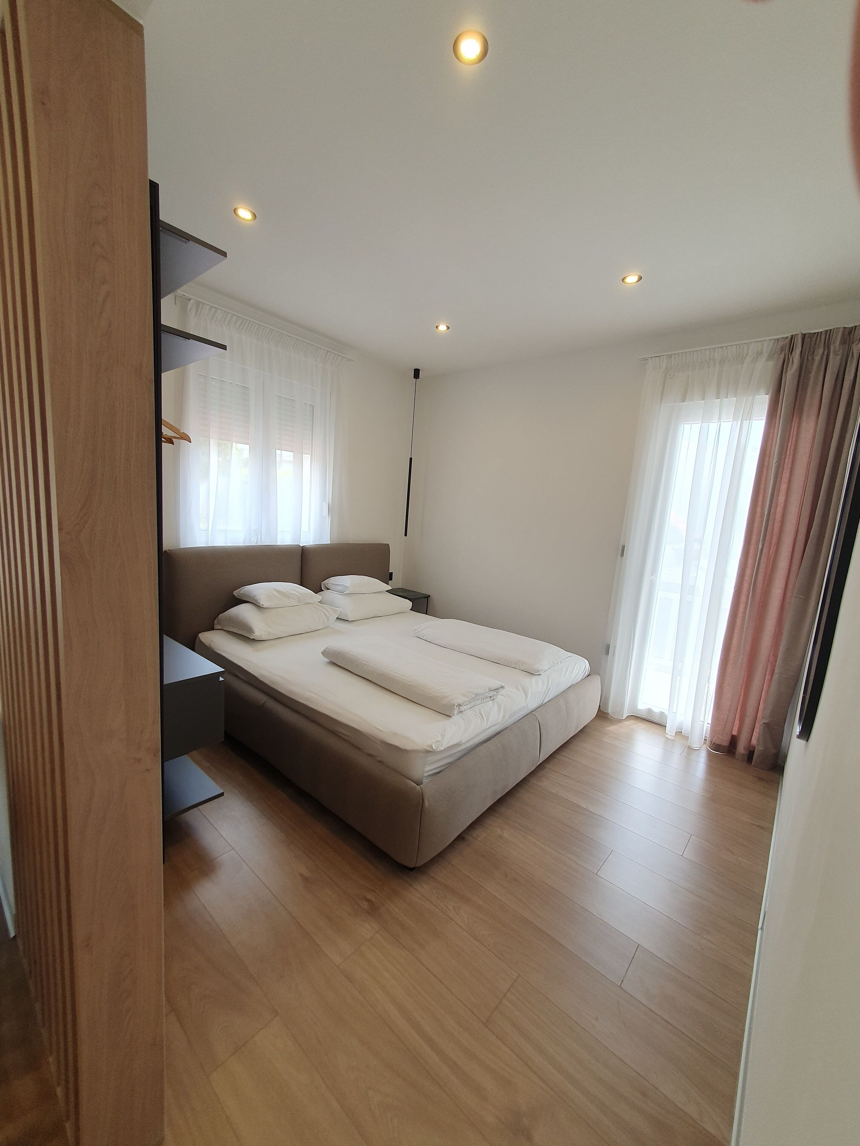 A bedroom with a bed, bedside tables, a wardrobe, and a window with curtains.