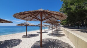 A beach with rows of thatched umbrellas and a sandy shore. - SmartStay Johnny (Podstrana)