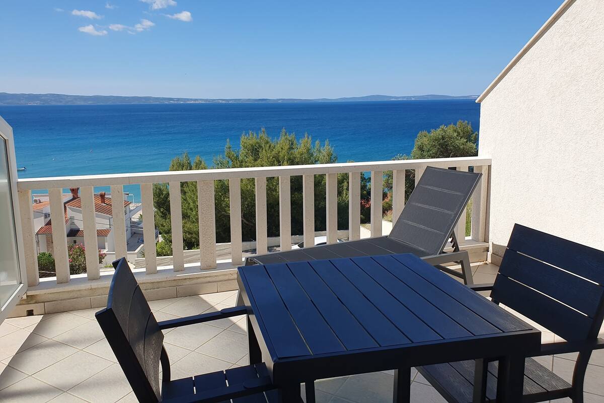 Un balcone con tavolo e sedie, con vista sulla costa.