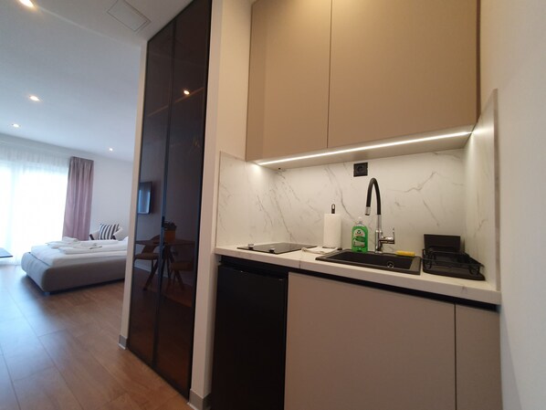 A modern hotel room with a kitchenette, a bed, and a view of the city. - SmartStay Johnny (Podstrana)