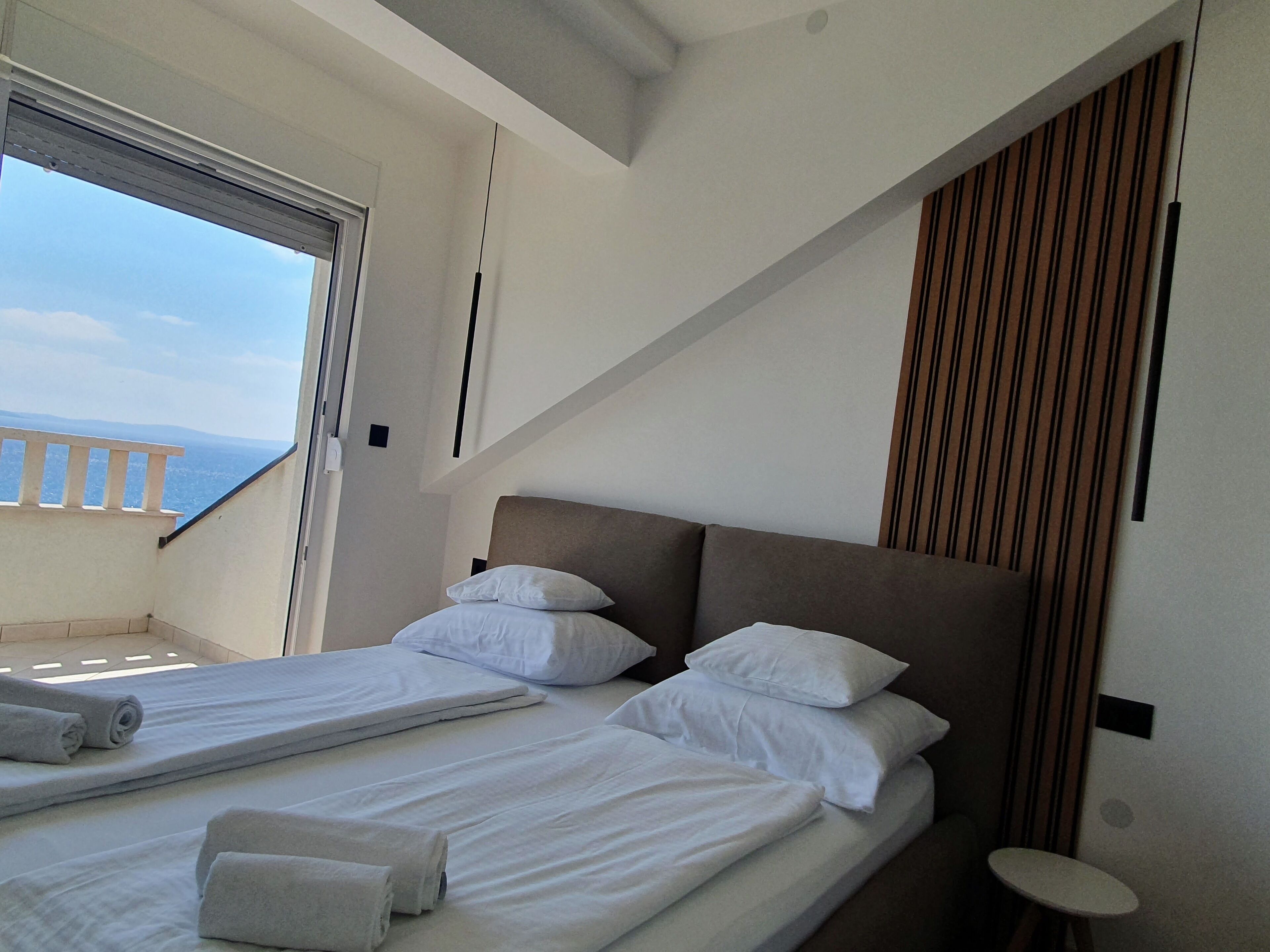 A hotel room with two beds, a balcony, and a view of the sea.