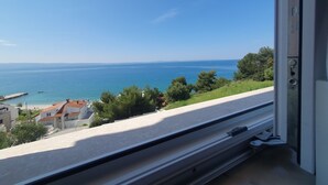 Vista desde una ventana con vistas a la costa, cielo despejado, agua y edificios a lo lejos.