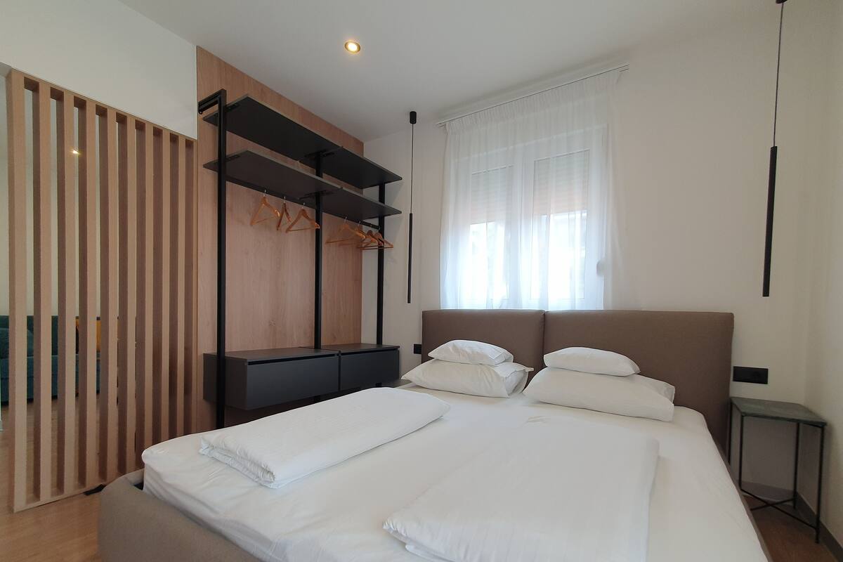 Una camera da letto moderna con un letto grande, un armadio in legno e una finestra con tende leggere.