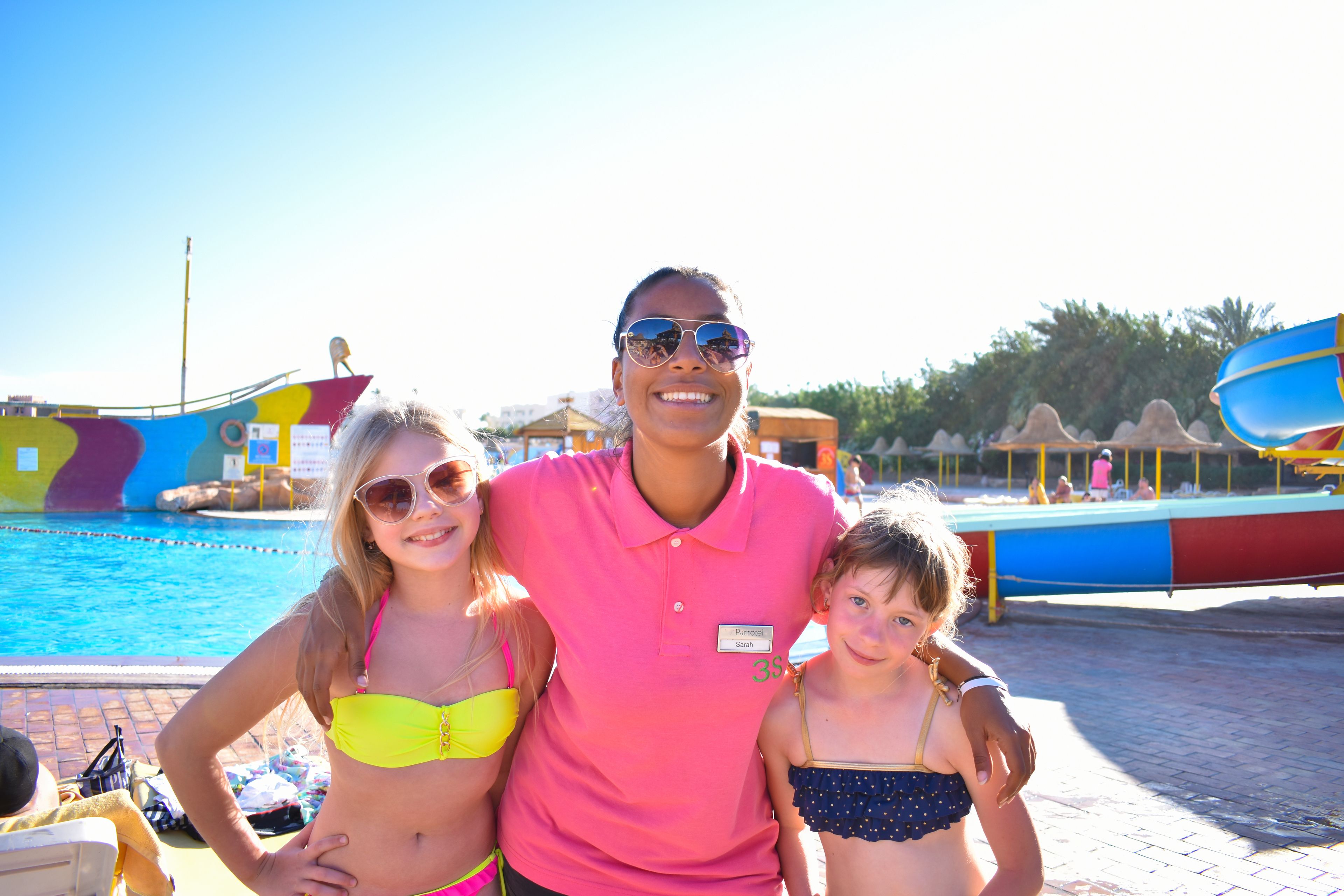 A pool area with a colorful boat structure and a water slide.