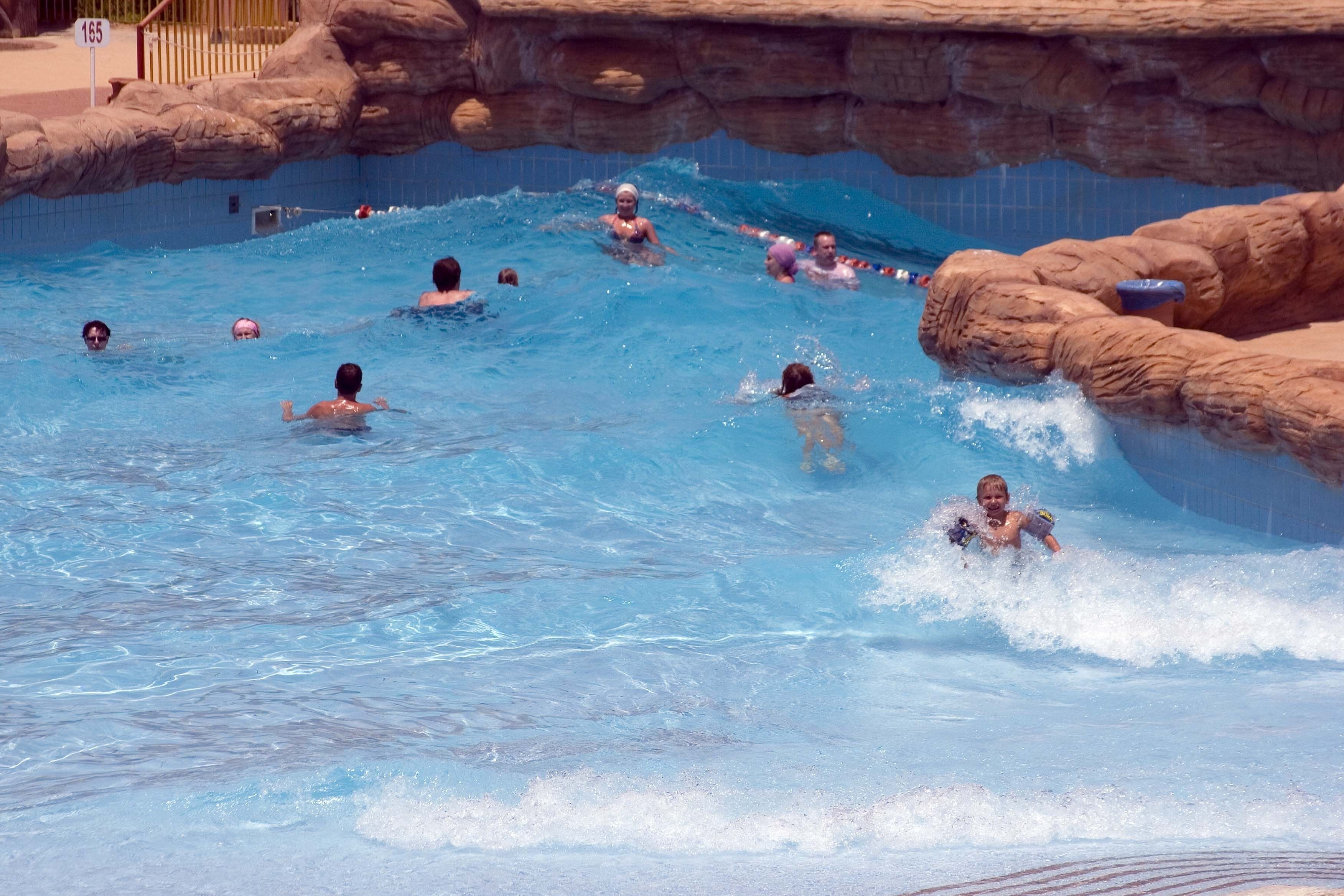 Una piscina con varias pistas y una pared rocosa.