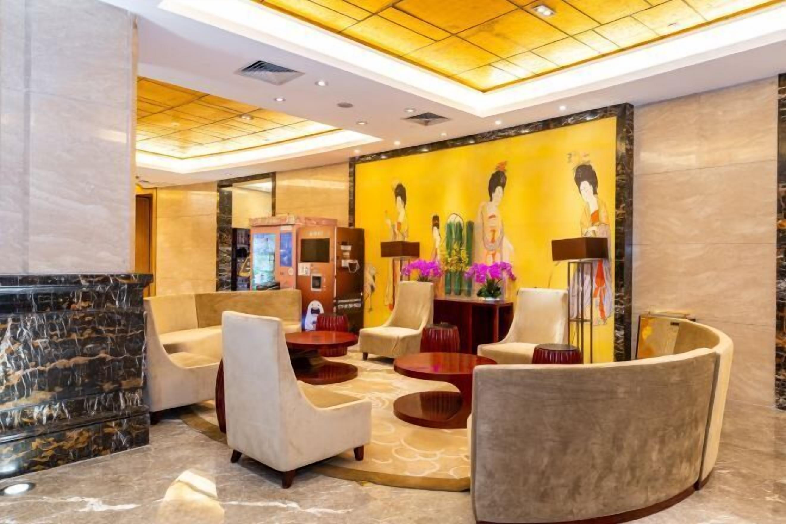 A lobby with a reception desk, seating area, and a wall with artwork.