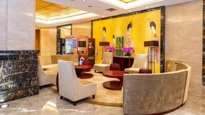 A lobby with a reception desk, seating area, and a wall with artwork.