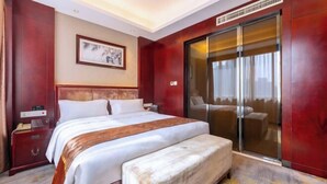 A hotel room with a large bed, a bedside table, a bench, a sliding glass door, and a framed picture on the wall.
