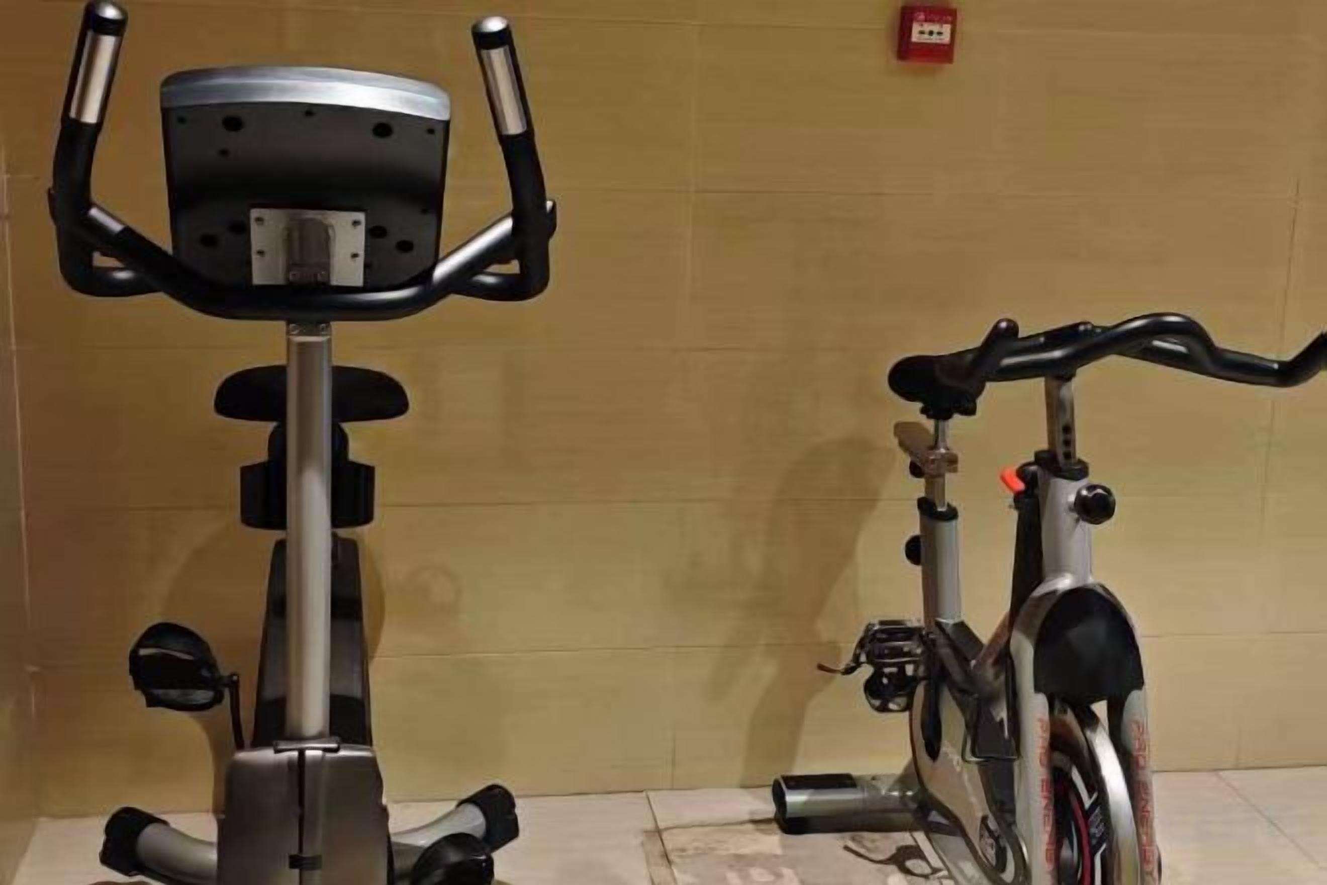 Ein Ergometer und ein Fahrrad in einem Raum mit Fliesenboden und einer schlichten Wand.
