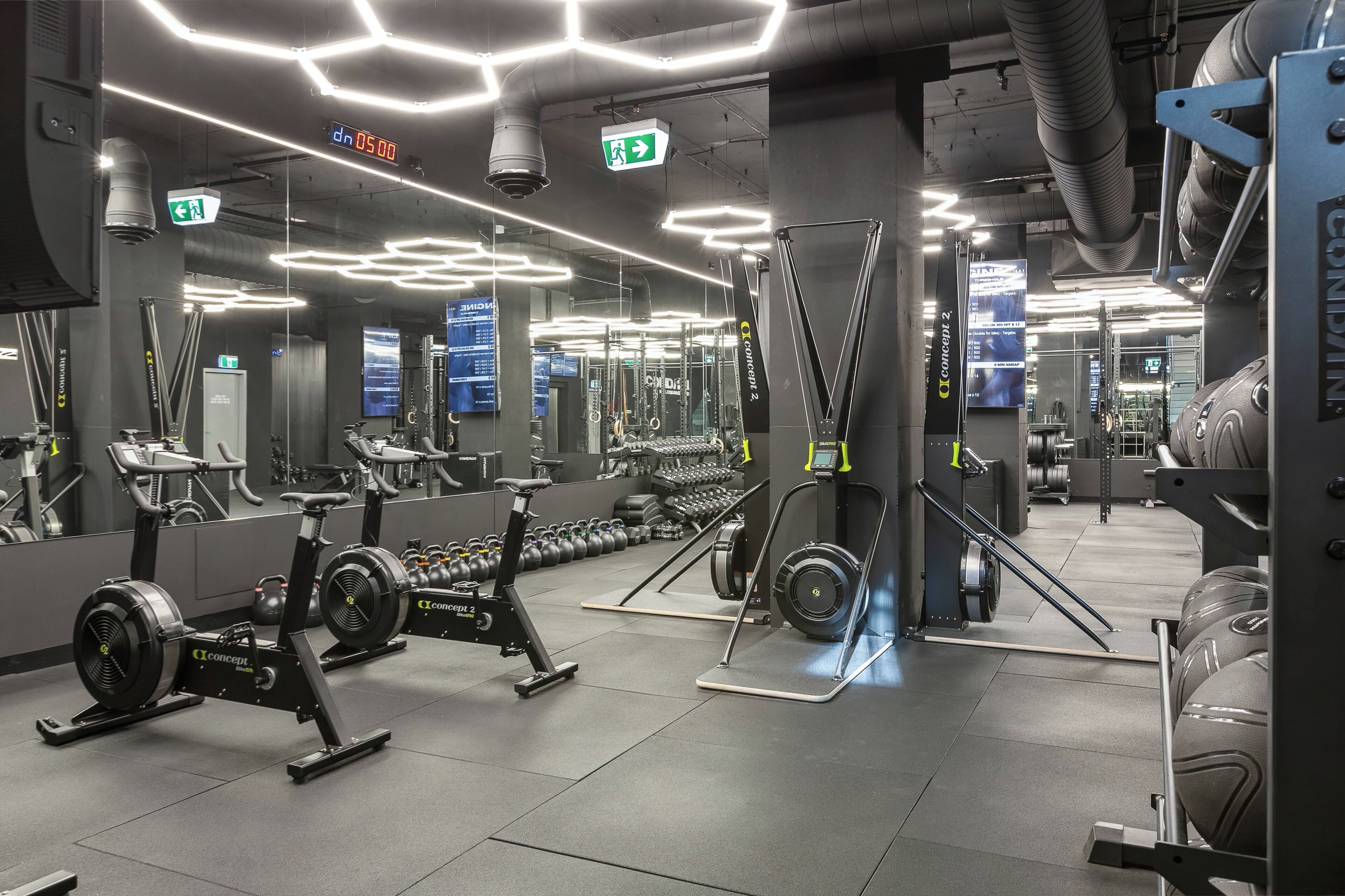 Ein modernes Fitnessstudio mit unterschiedlichen Trainingsgeräten, darunter Laufbänder, Ergometer und Kraftgeräte.