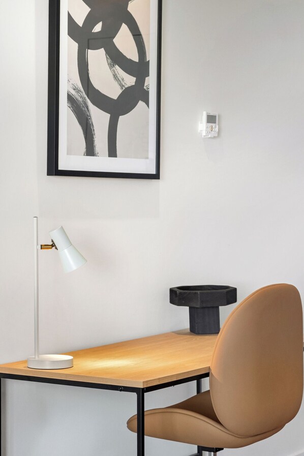 A modern office space with a desk, chair, lamp, and abstract artwork on the wall.