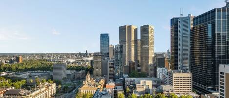 Un paisaje urbano con edificios modernos altos, un edificio histórico con cúpula y una combinación de espacios urbanos y verdes.