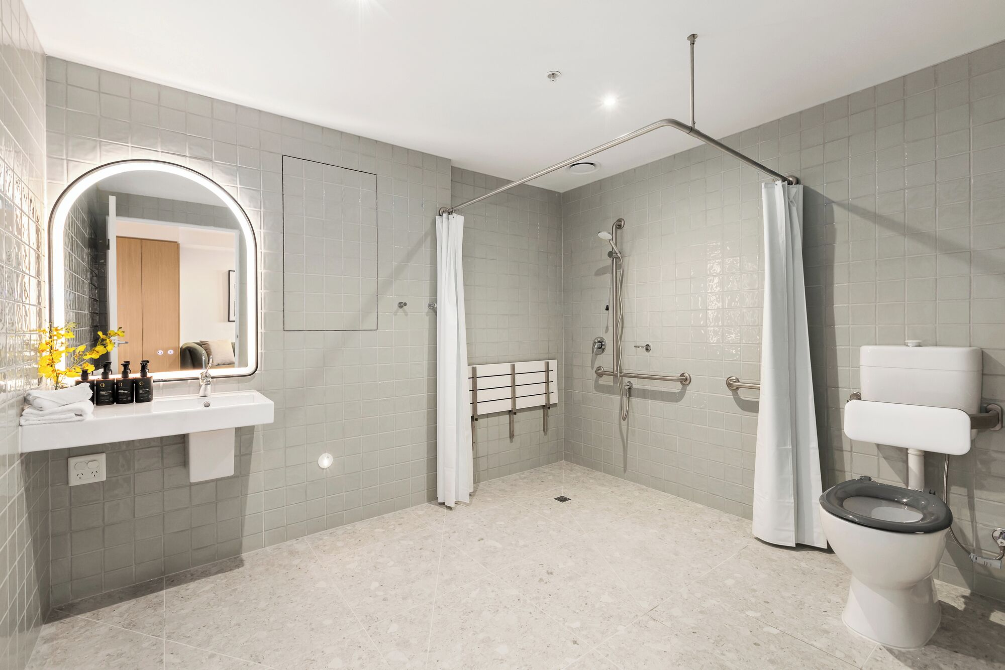 A modern bathroom with a shower, toilet, and sink.