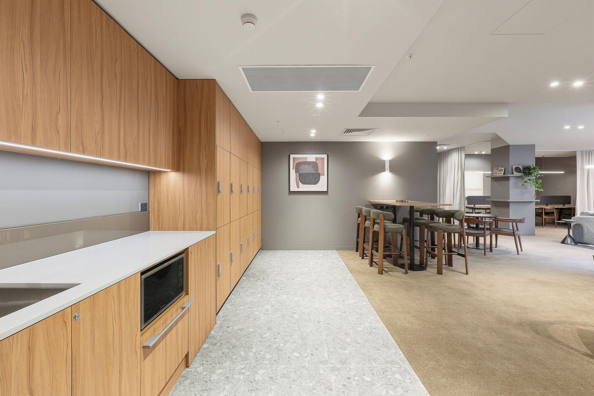 A modern kitchen with wooden cabinets, a built-in oven, and a long countertop.