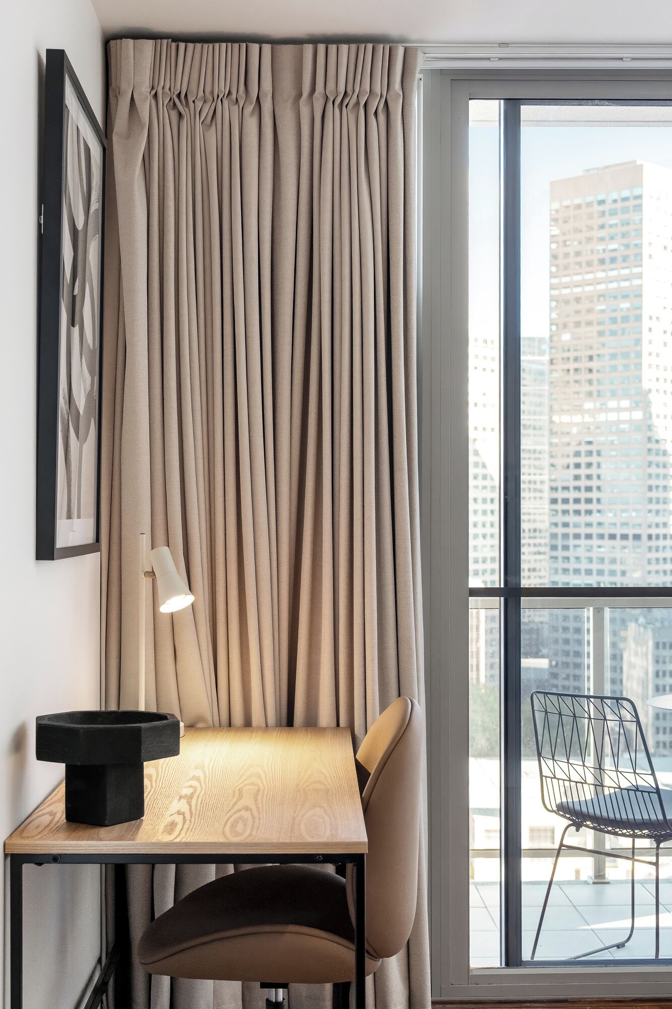 A modern room with a large window, a desk, a chair, and a lamp.