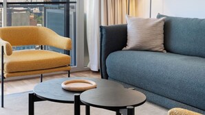 A modern hotel room with a sofa, armchair, and a small table.