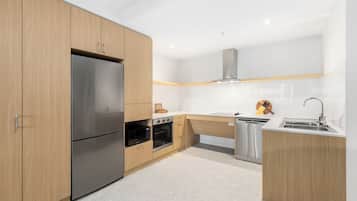 A modern kitchen with wooden cabinets, stainless steel appliances, and a white countertop.