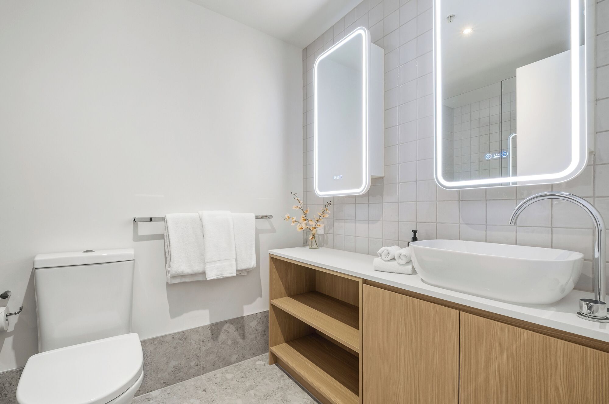 A modern bathroom with a white sink, vanity, and toilet.