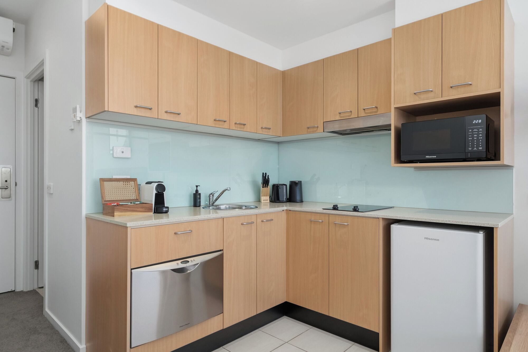 A compact kitchen with wooden cabinets, a dishwasher, a microwave, and a sink.